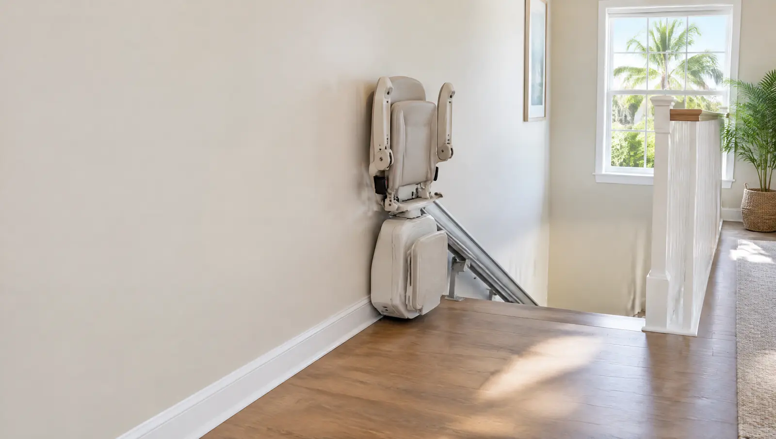Stair lift parked at the top landing with its seat, arms and footrest folded up