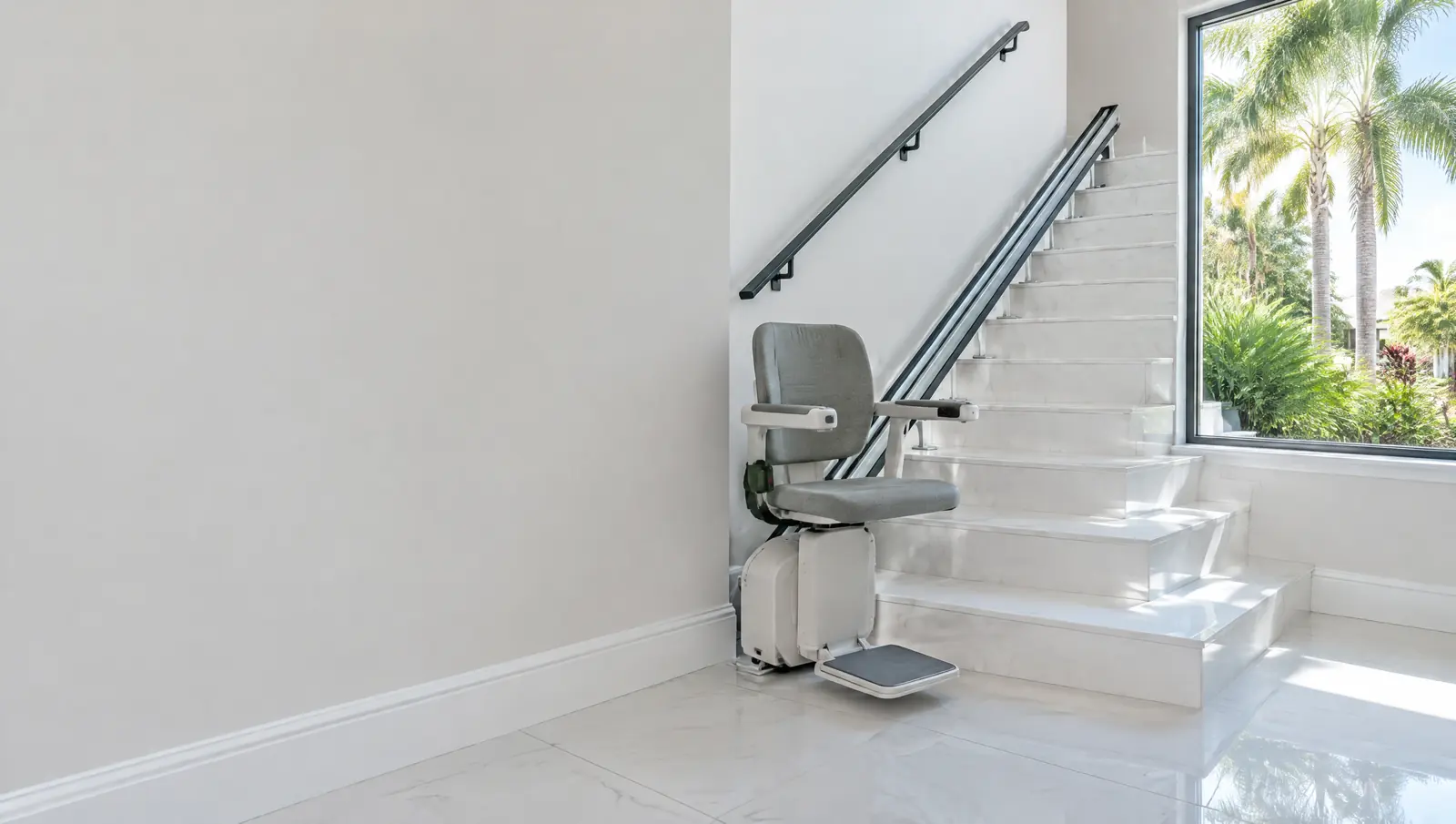 Straight stair lift on a staircase with white porcelain tile treads and a black metal handrail