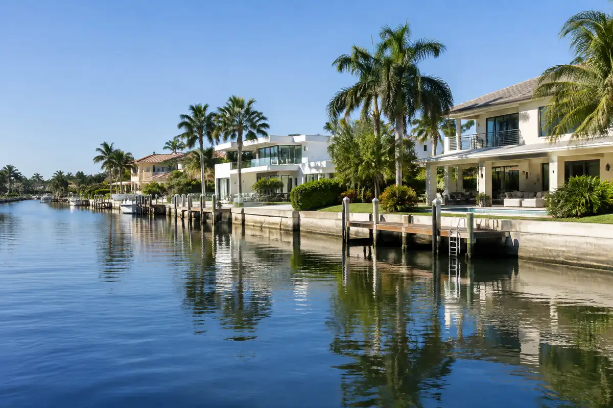 Waterfront homes with seawalls and docks along a calm Fort Lauderdale canal lined with palms