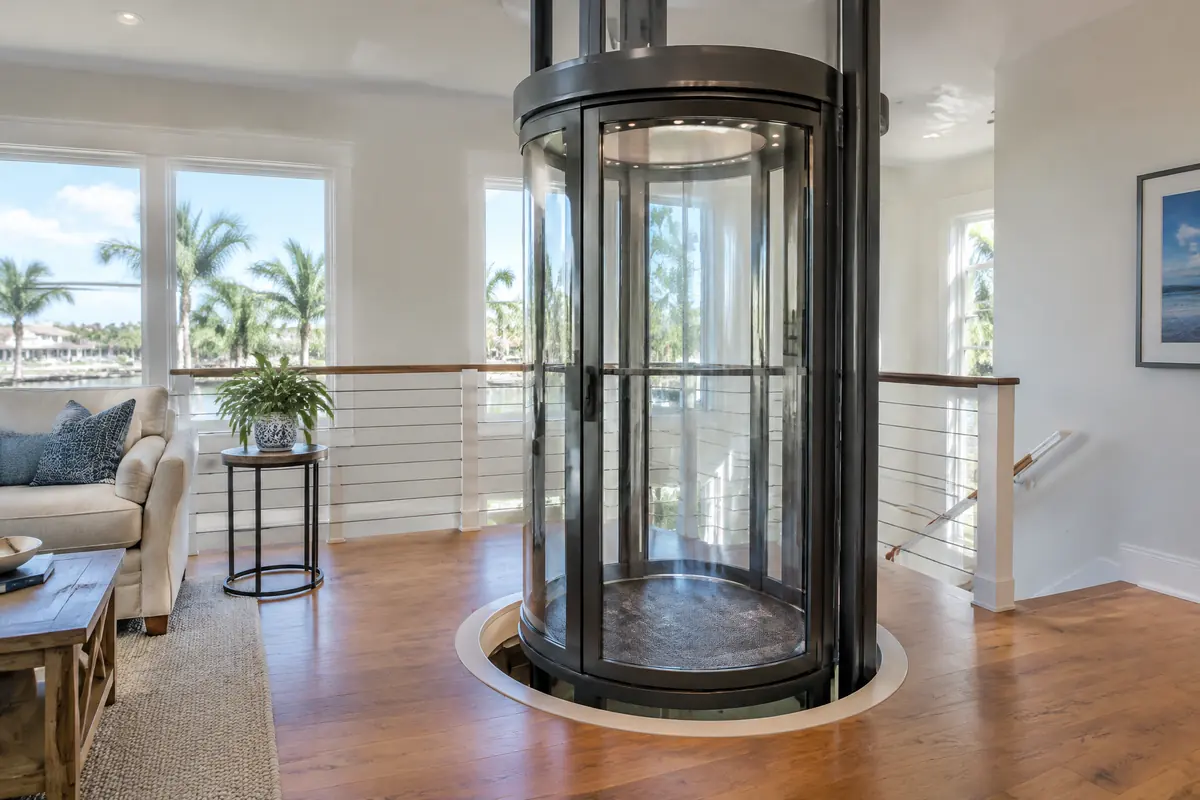 Top of a round transparent pneumatic elevator tube on an upper floor, with the cab arriving