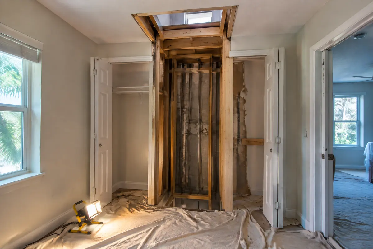 Stacked closet space opened during a retrofit, with a framed floor opening for a future elevator