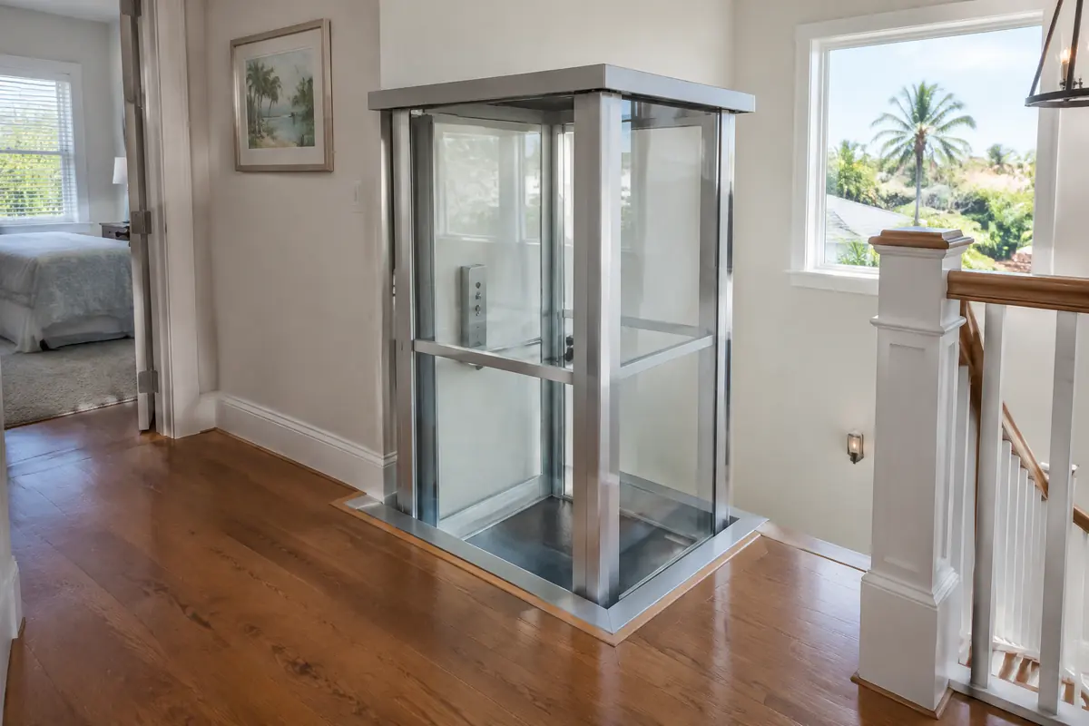 Compact shaftless lift arriving through a neat opening in an upstairs floor, with clear guard panels